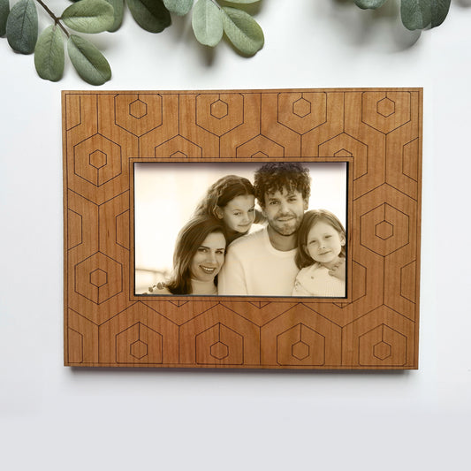 Wooden picture frame with geometric patterns holding a family photo on a white background.