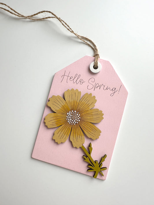 Pink tag with a yellow flower design and 'Hello Spring!' text on a light gray background
