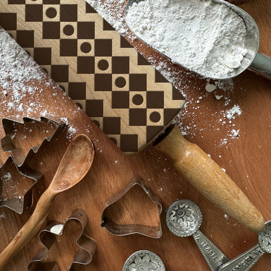 Baking tools including cookie cutters and a rolling pin on a wooden surface with flour.