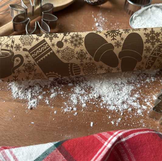 Decorative rolling pin with winter-themed design on a wooden surface with flour.
