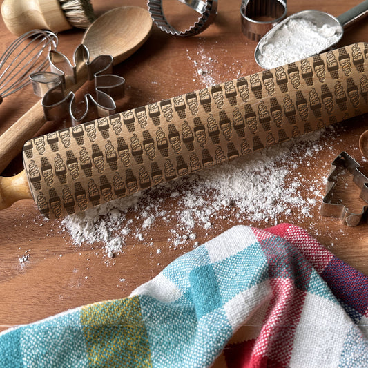 Decorative rolling pin with ice cream pattern on a wooden surface with baking tools.