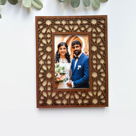 Wooden photo frame with intricate cut-out design, holding a wedding photograph of a couple.