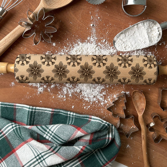 Wooden rolling pin with star patterns on a wooden surface with flour and kitchen tools.
