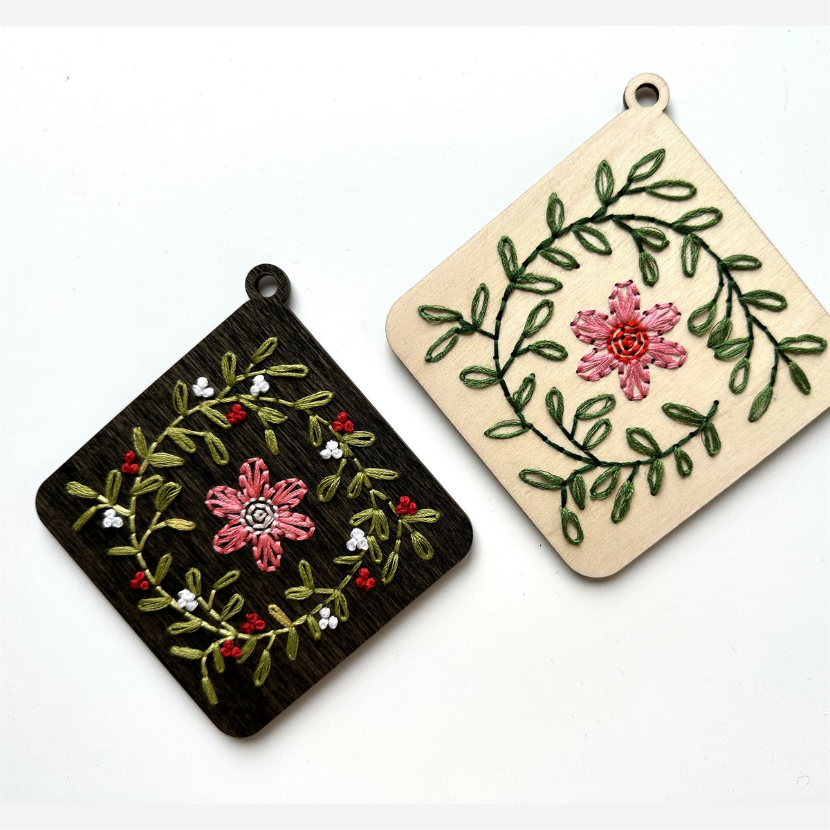 Dark stained and light wood floral wreath embroidery ornaments laid flat on a white background