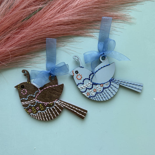 Brown stained and pale blue songbird embroidery ornaments with blue ribbons and pink pampas grass