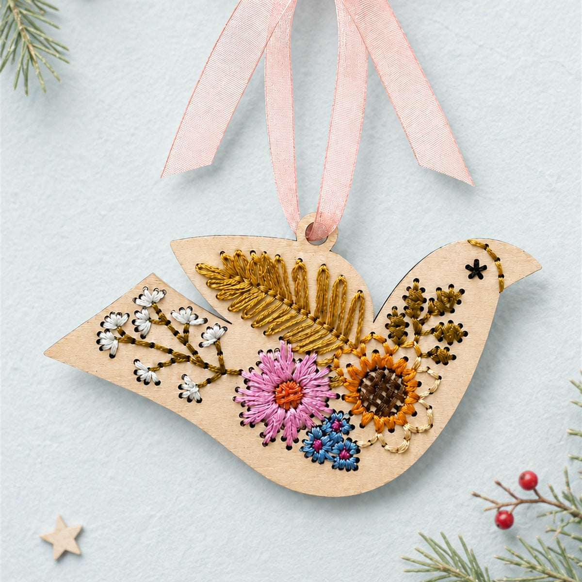Folk floral bird embroidery ornament, light wood dove with pink, orange and gold flower stitching and a pink ribbon