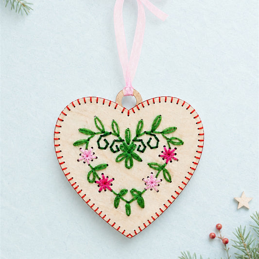 Folk art heart embroidery ornament, light wood heart with red blanket stitch edge, green and pink flowers and a pink ribbon
