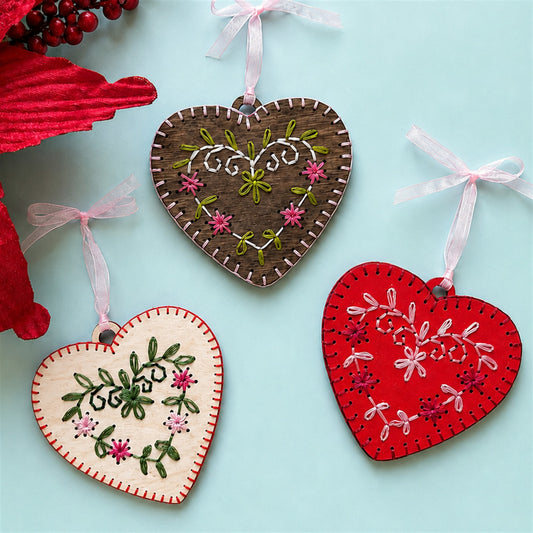 Light wood, brown stained and red heart embroidery ornaments with a red poinsettia on a pale blue background
