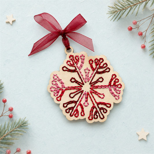 Folk art snowflake embroidery ornament, scalloped light wood snowflake with red stitching and a burgundy ribbon