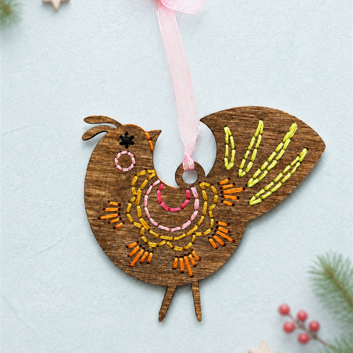 Scalloped folk bird embroidery ornament, brown stained wood bird with orange and yellow stitching and a pink ribbon