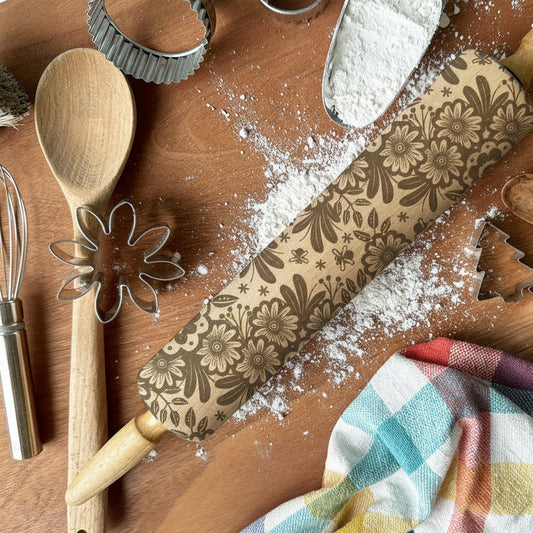 Baking tools and utensils on a wooden surface with flour, including a rolling pin and cookie cutters, with 'Pickleandpeachstudio' branding.