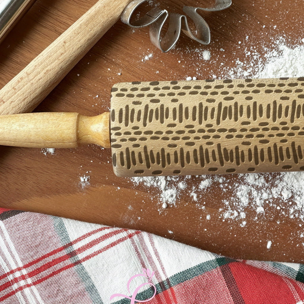 Wooden rolling pin with decorative pattern on a wooden surface with flour and plaid fabric.