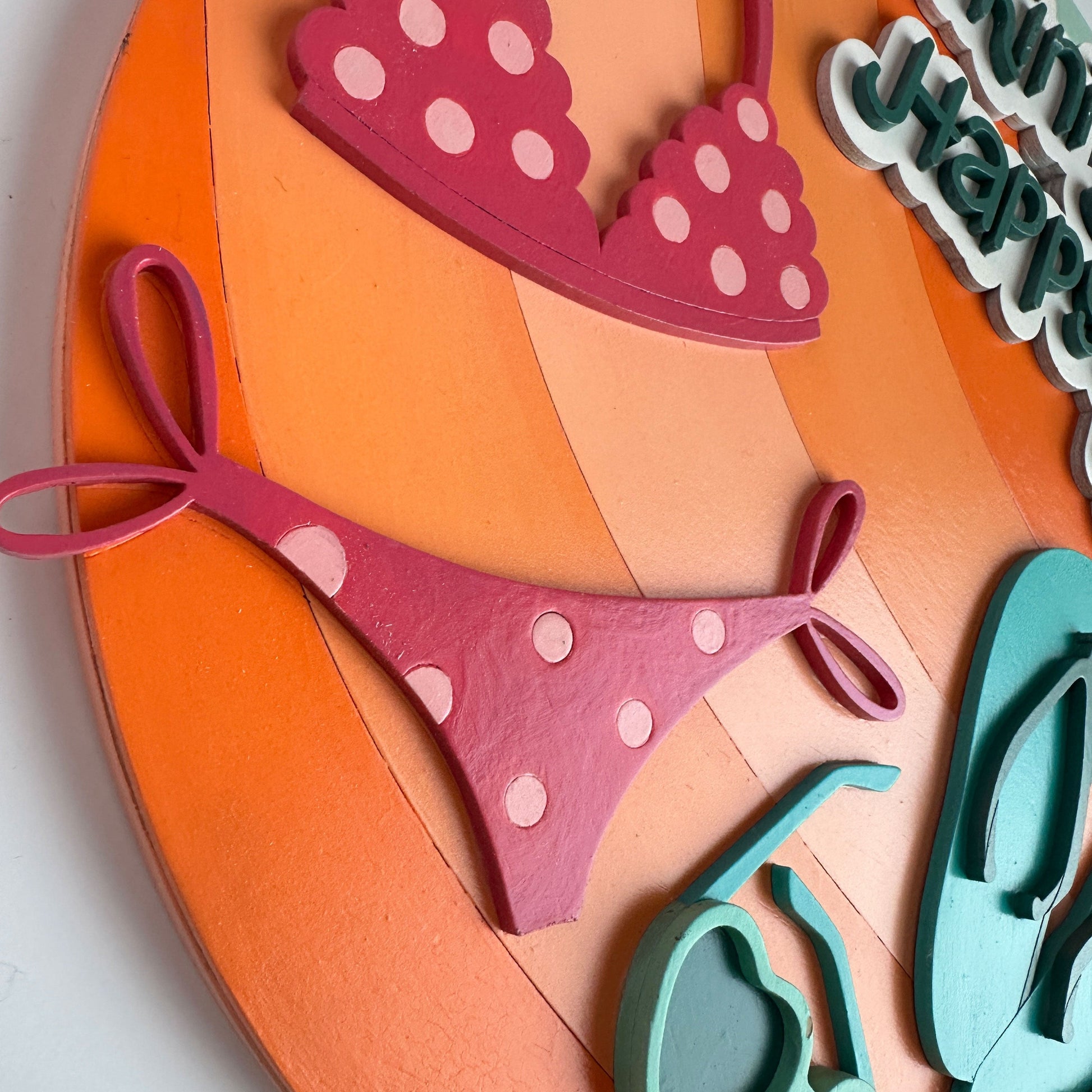 Pink polka dot bikini cutout on an orange background with sunglasses and text.