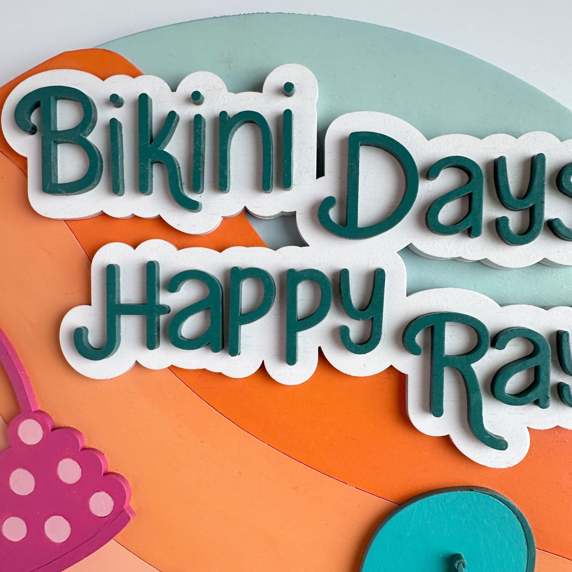 Colorful cutout letters spelling 'Bikini Days Happy Rave' on a geometric background.