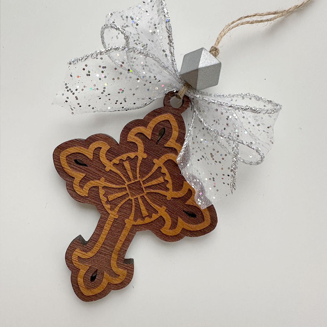 Decorative wooden cross ornament with a silver bow on a white background