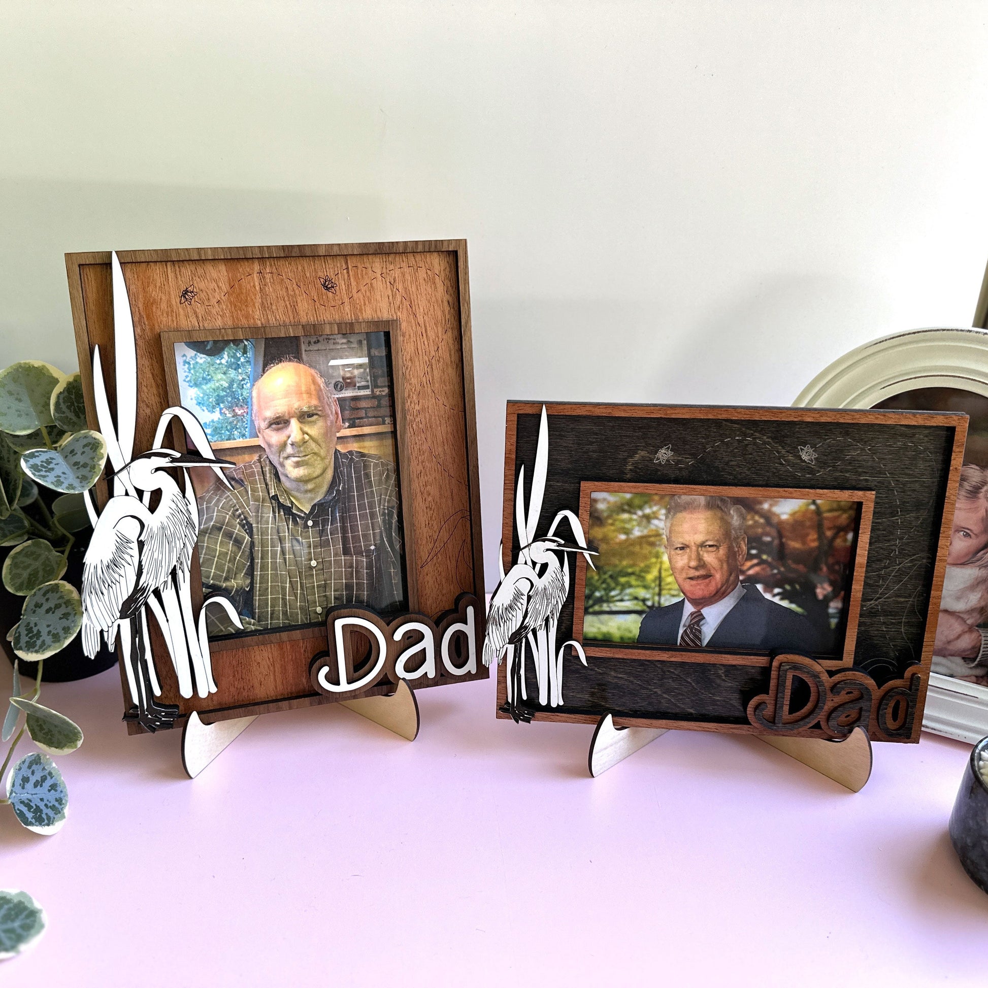 Two wooden photo frames with cut-out letters spelling 'Dad' on a white surface.