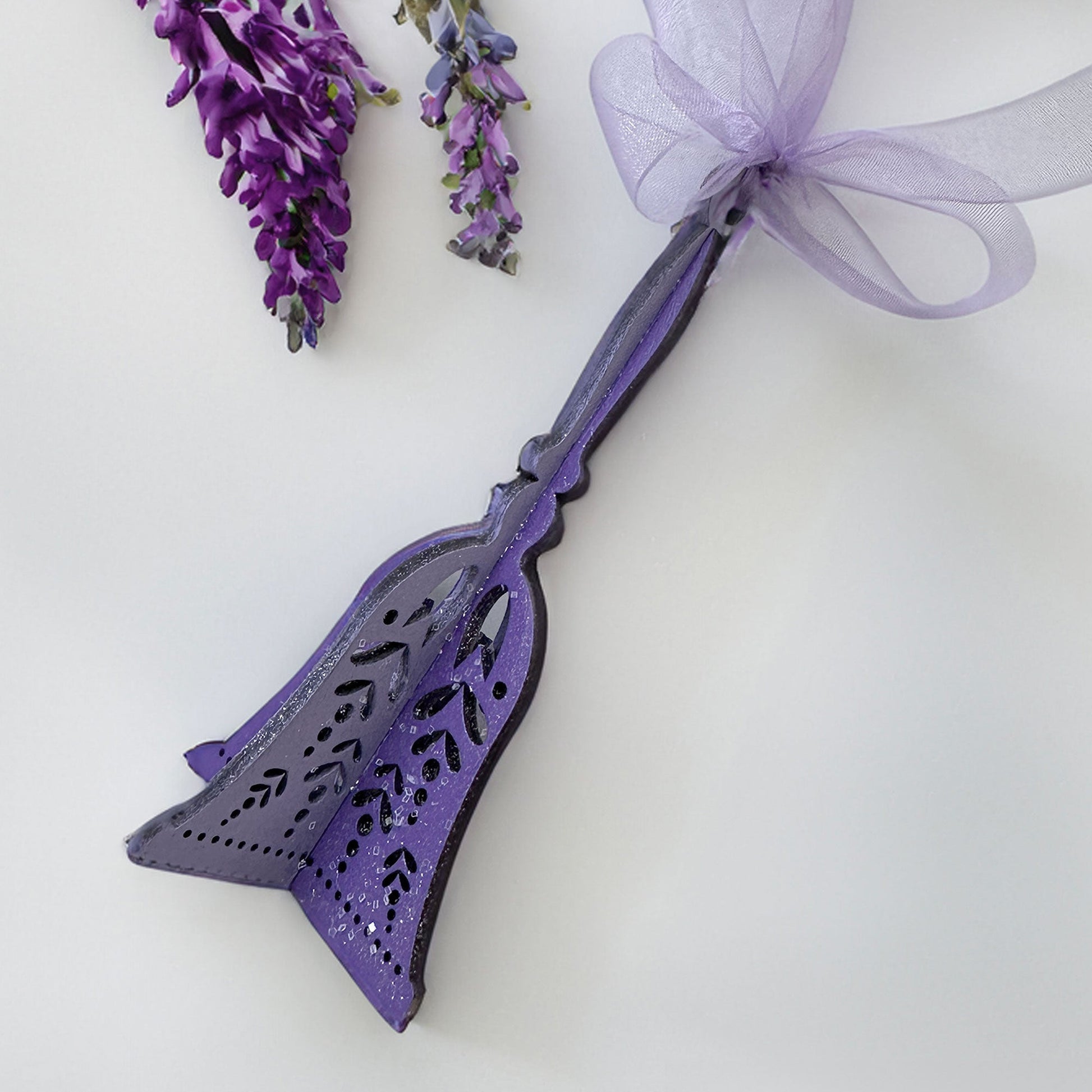 Decorative purple broom with a bow and lavender flowers on a white background