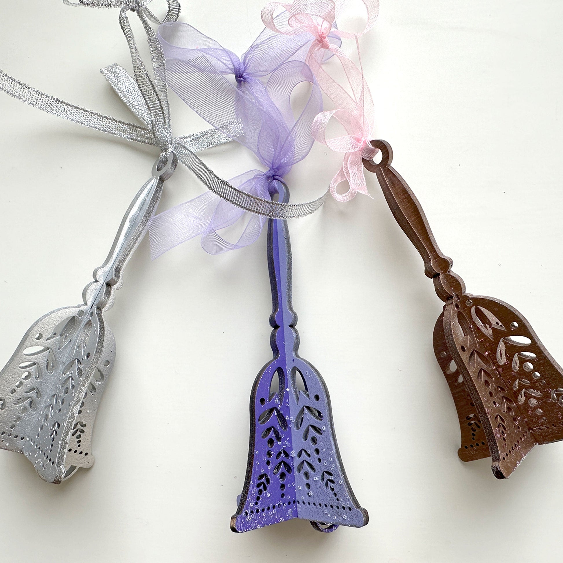 Three decorative bells with ribbons on a white background