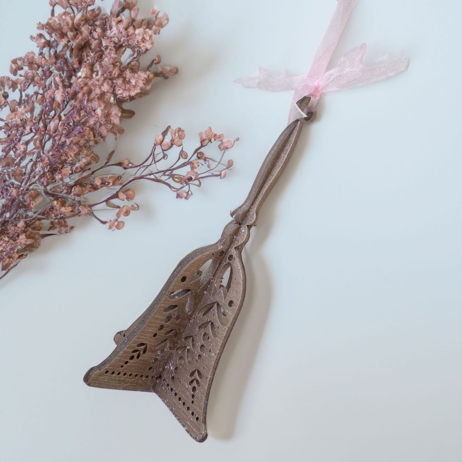Decorative metal cake server with intricate designs on a light background with pink flowers.