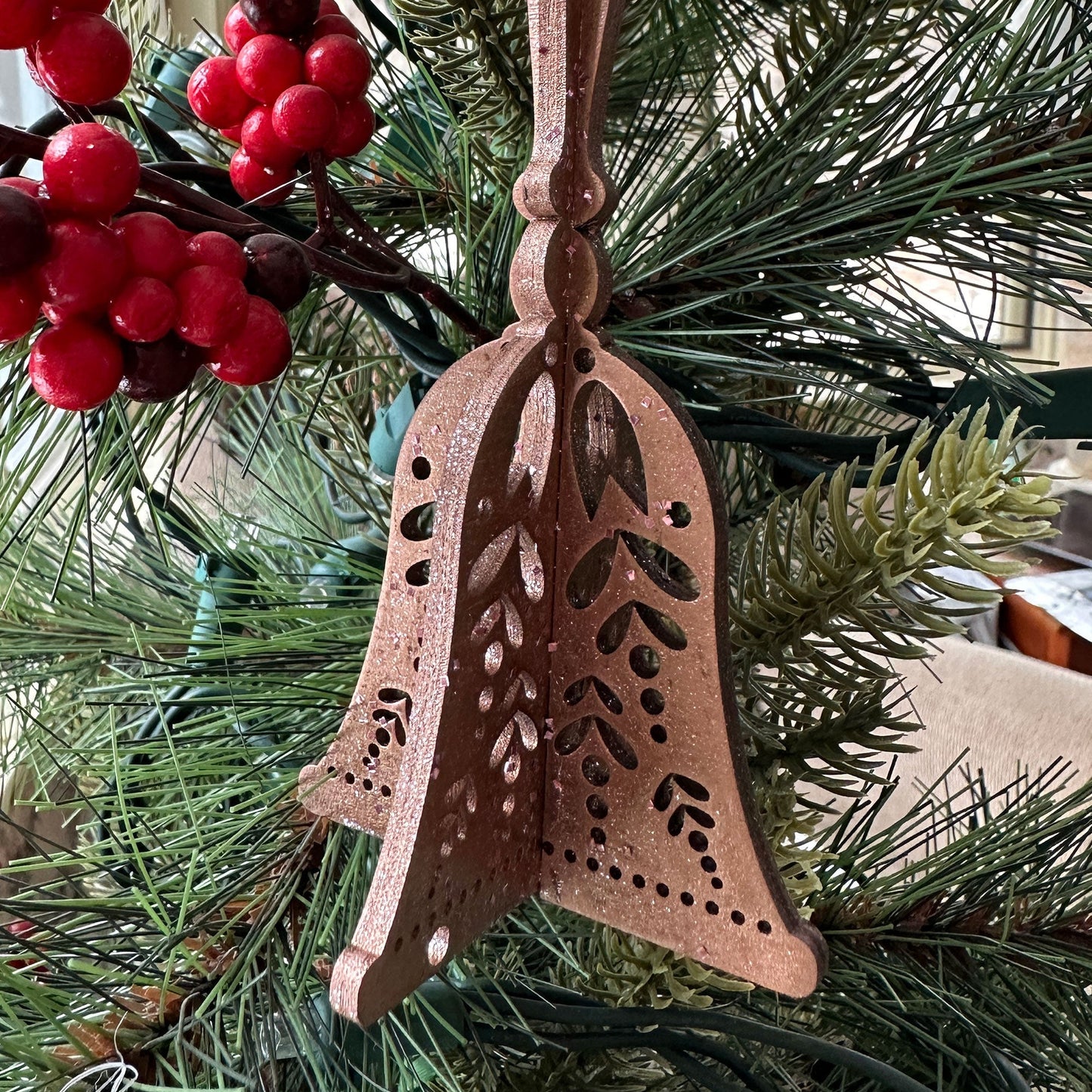 Decorative bell ornament on a Christmas tree with red berries