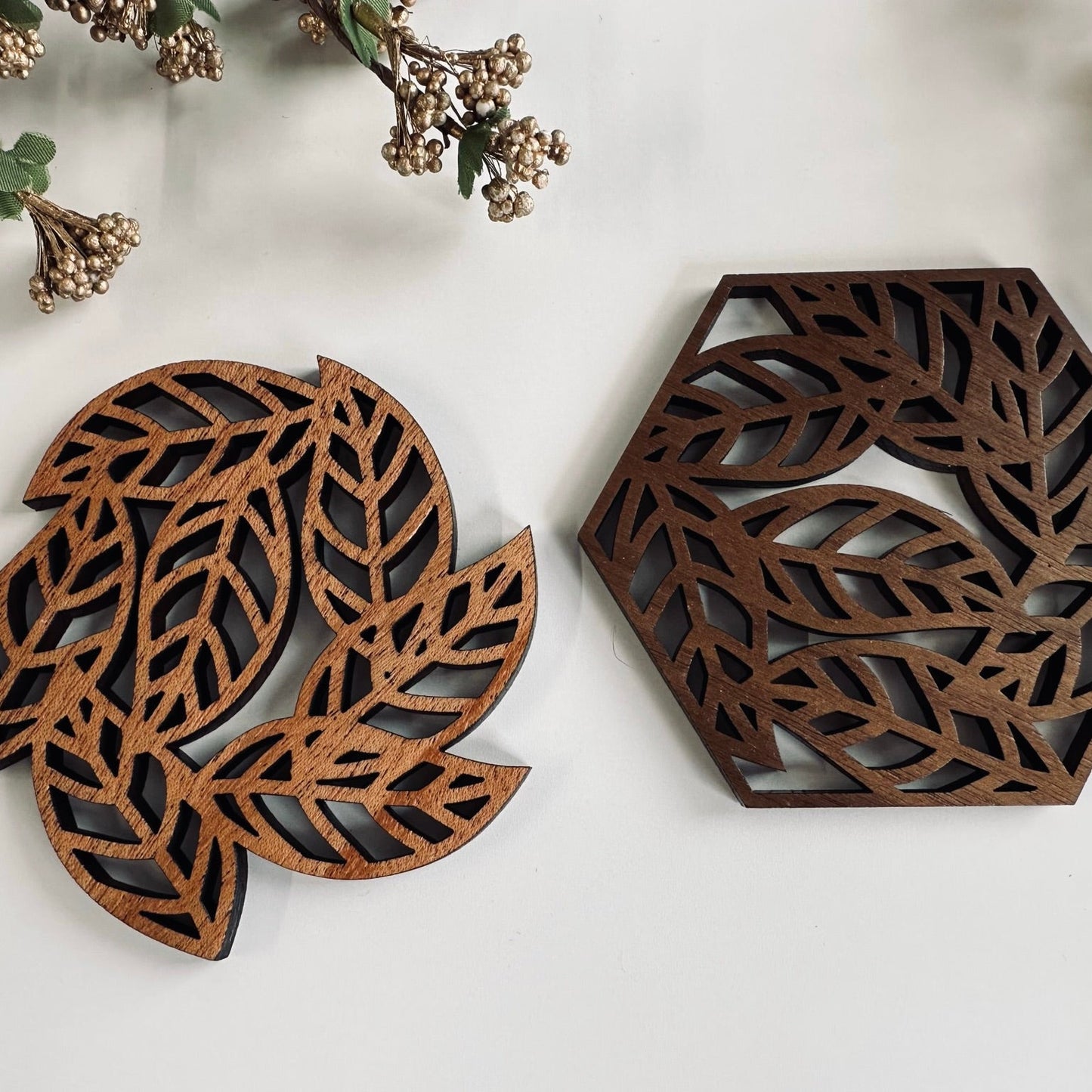 Decorative wooden coaster pieces with leaf patterns on a light background