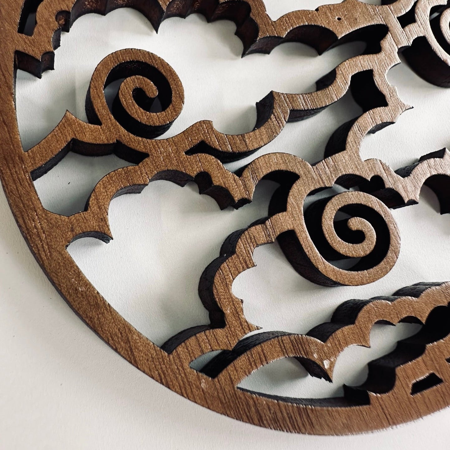Wooden decorative coaster with intricate patterns on a light background