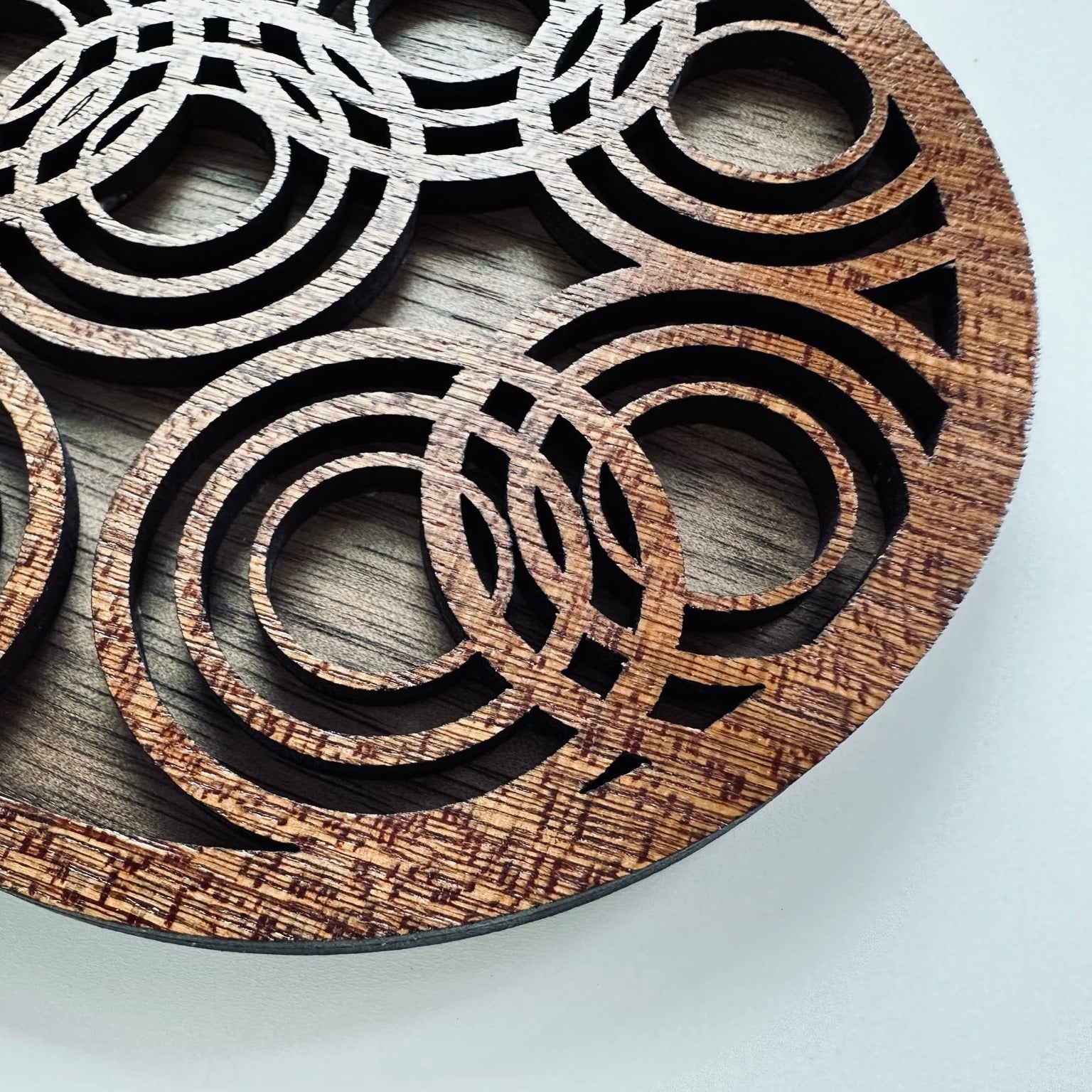 Wooden coaster with circular cutout design on a light gray background