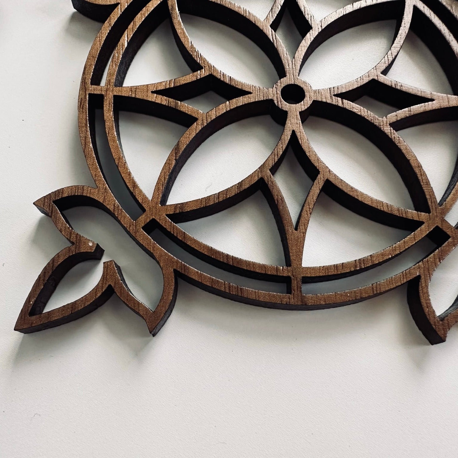 Decorative wooden coaster with intricate cut-out patterns on a white background