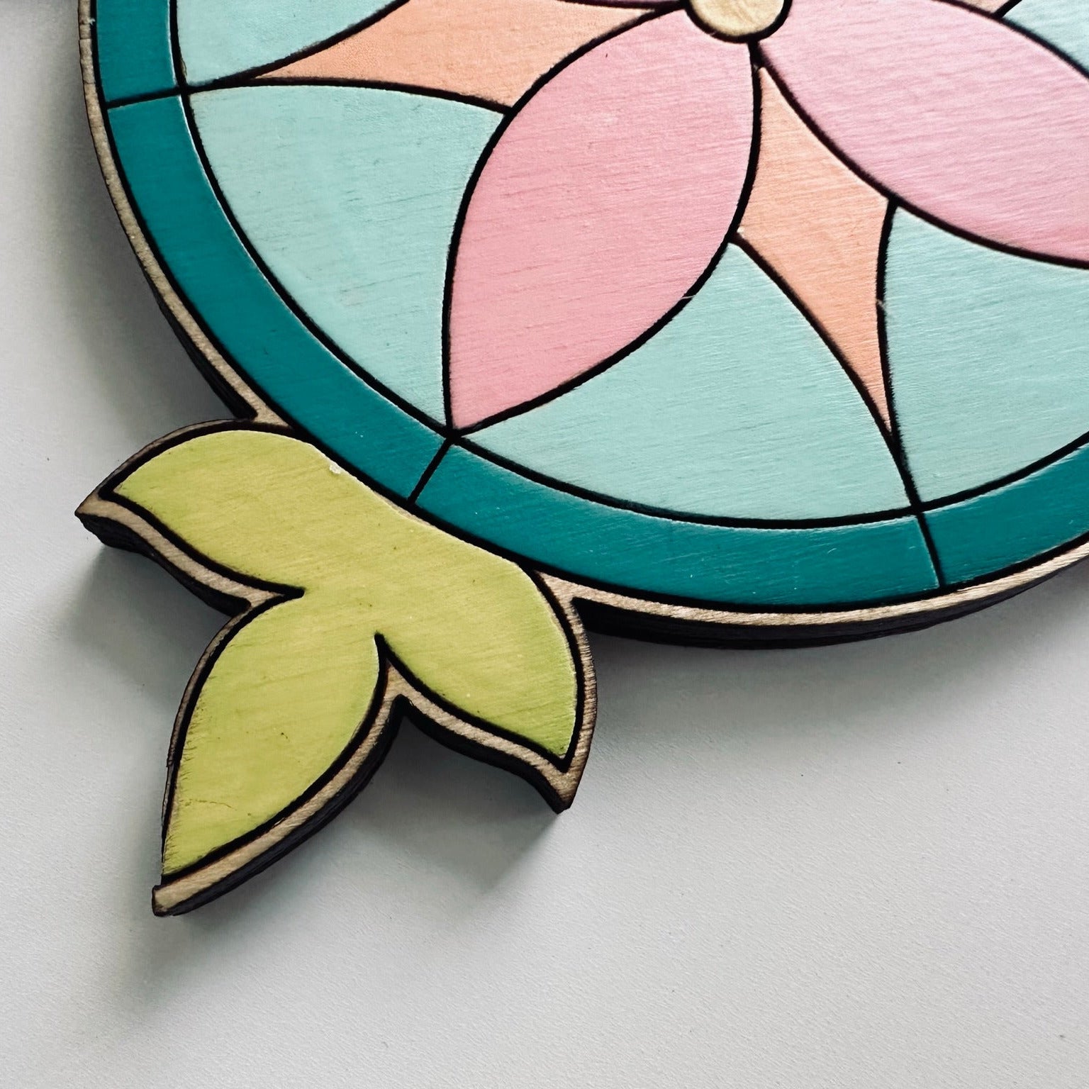 Colorful wooden coaster with a stained glass design on a light gray background