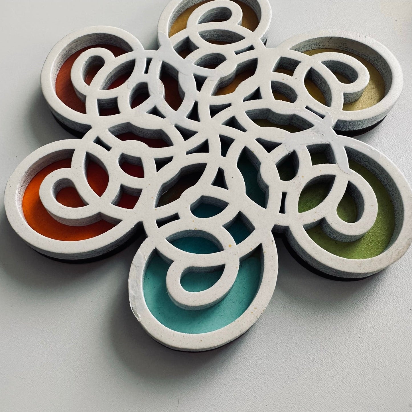 Decorative coaster with interlocking circular designs in various colors on a gray background