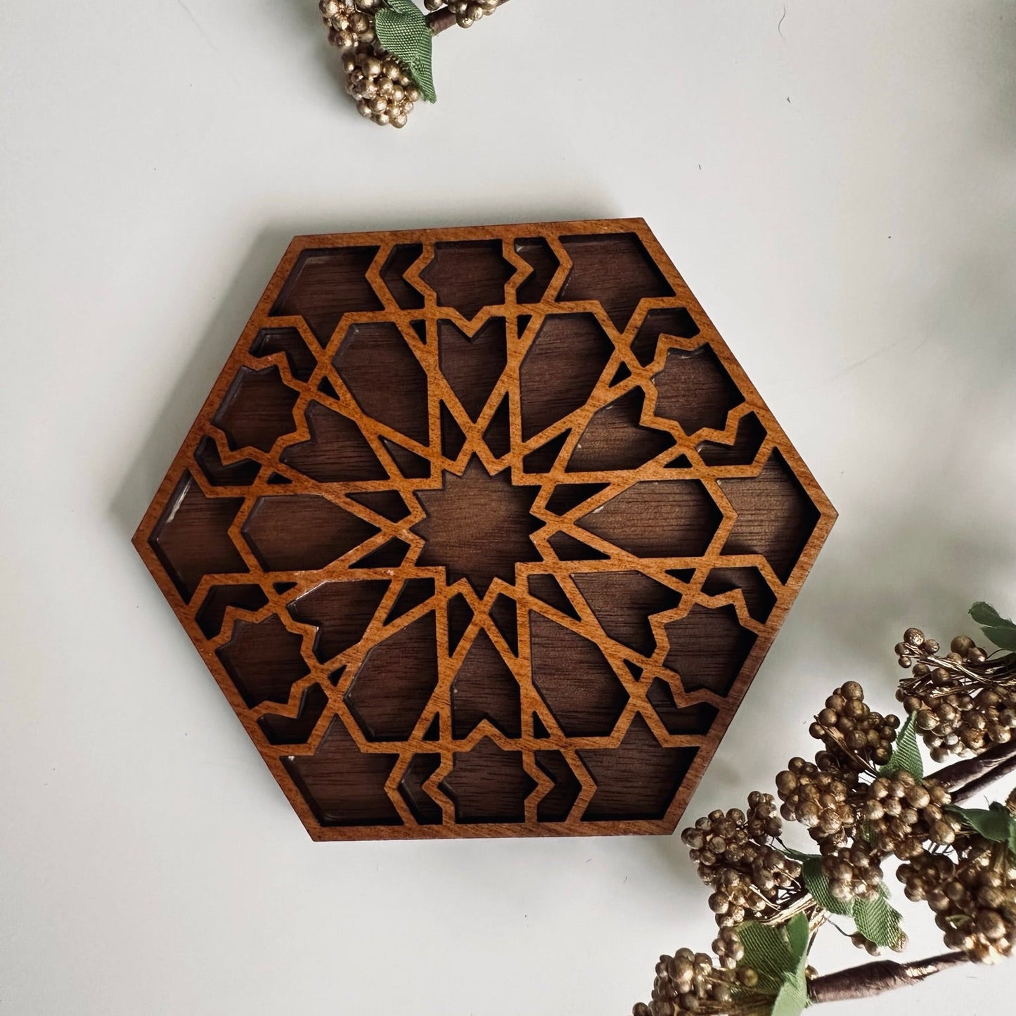Hexagonal wooden decorative coaster with intricate patterns on a light background