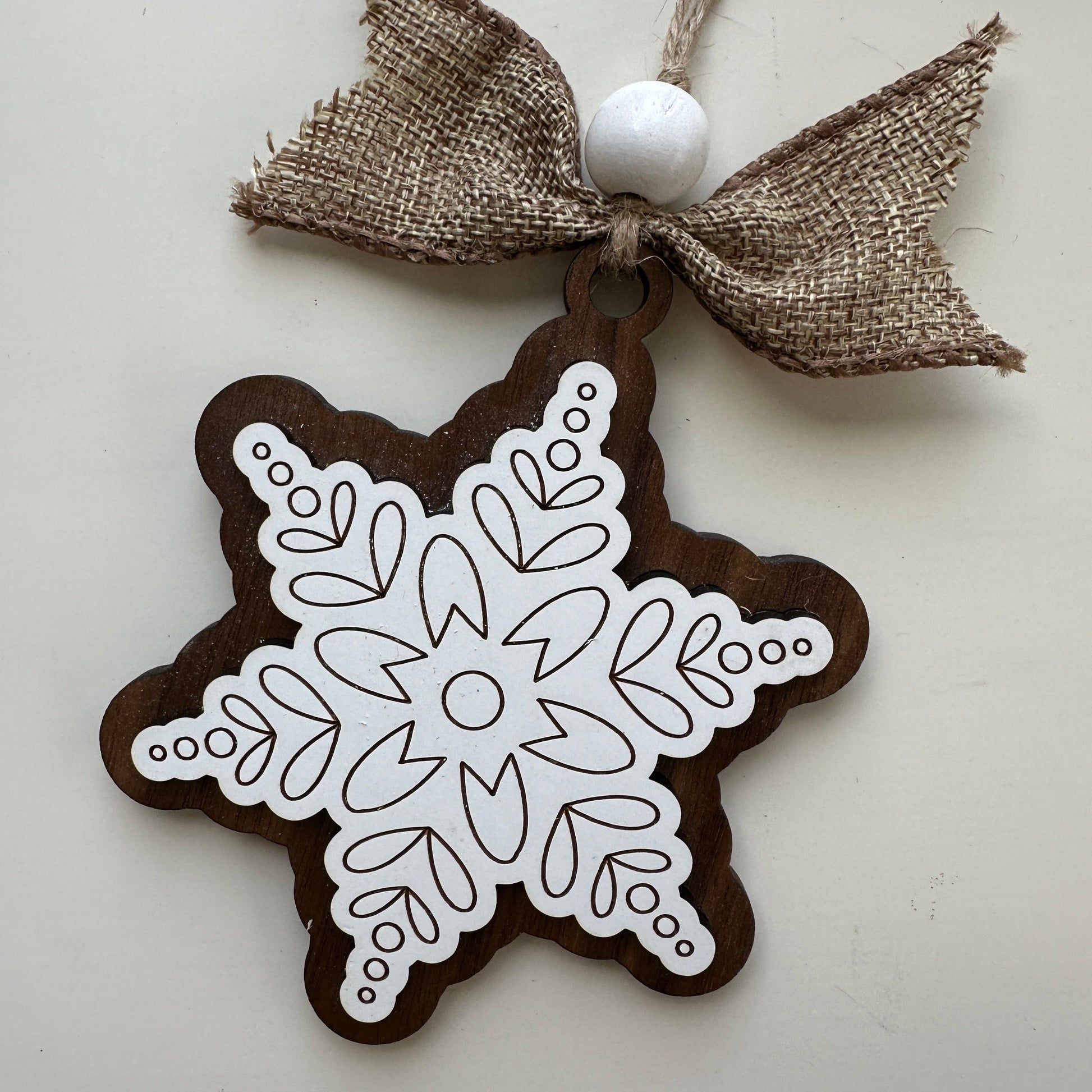 Decorative snowflake ornament with burlap ribbon on a light background