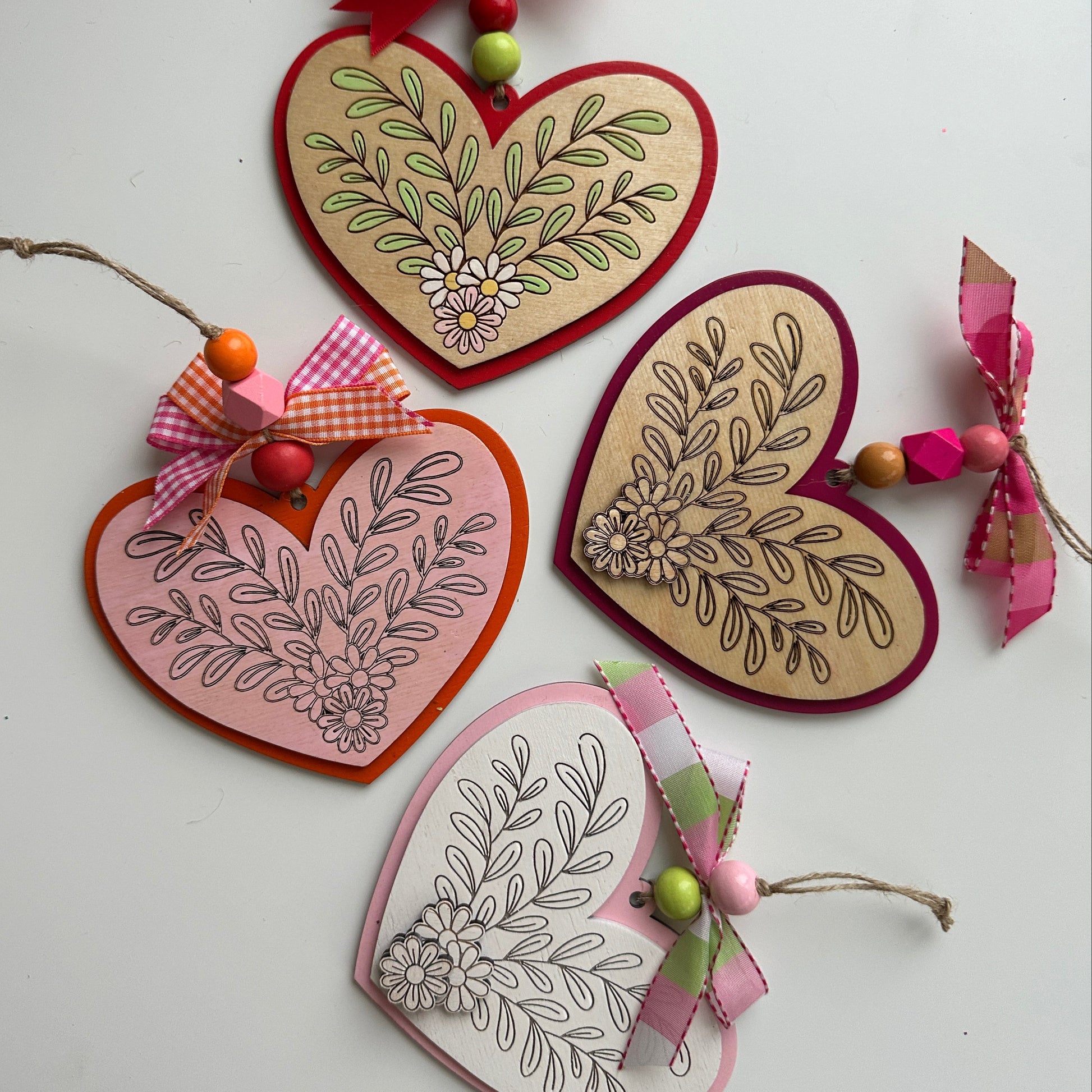 Heart-shaped decorations with floral patterns and ribbons on a white surface