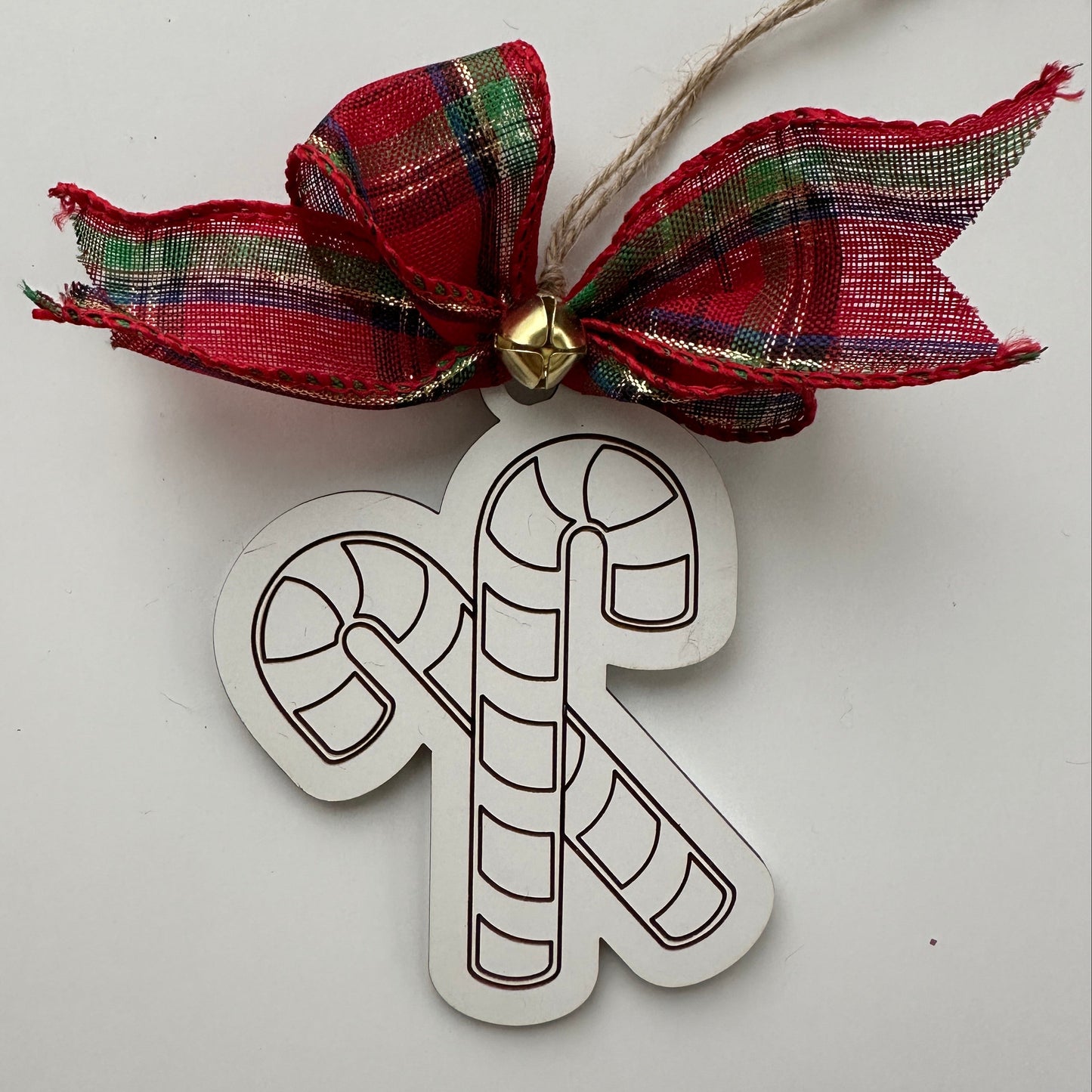 Christmas ornament with candy cane design and plaid bow on a white background.