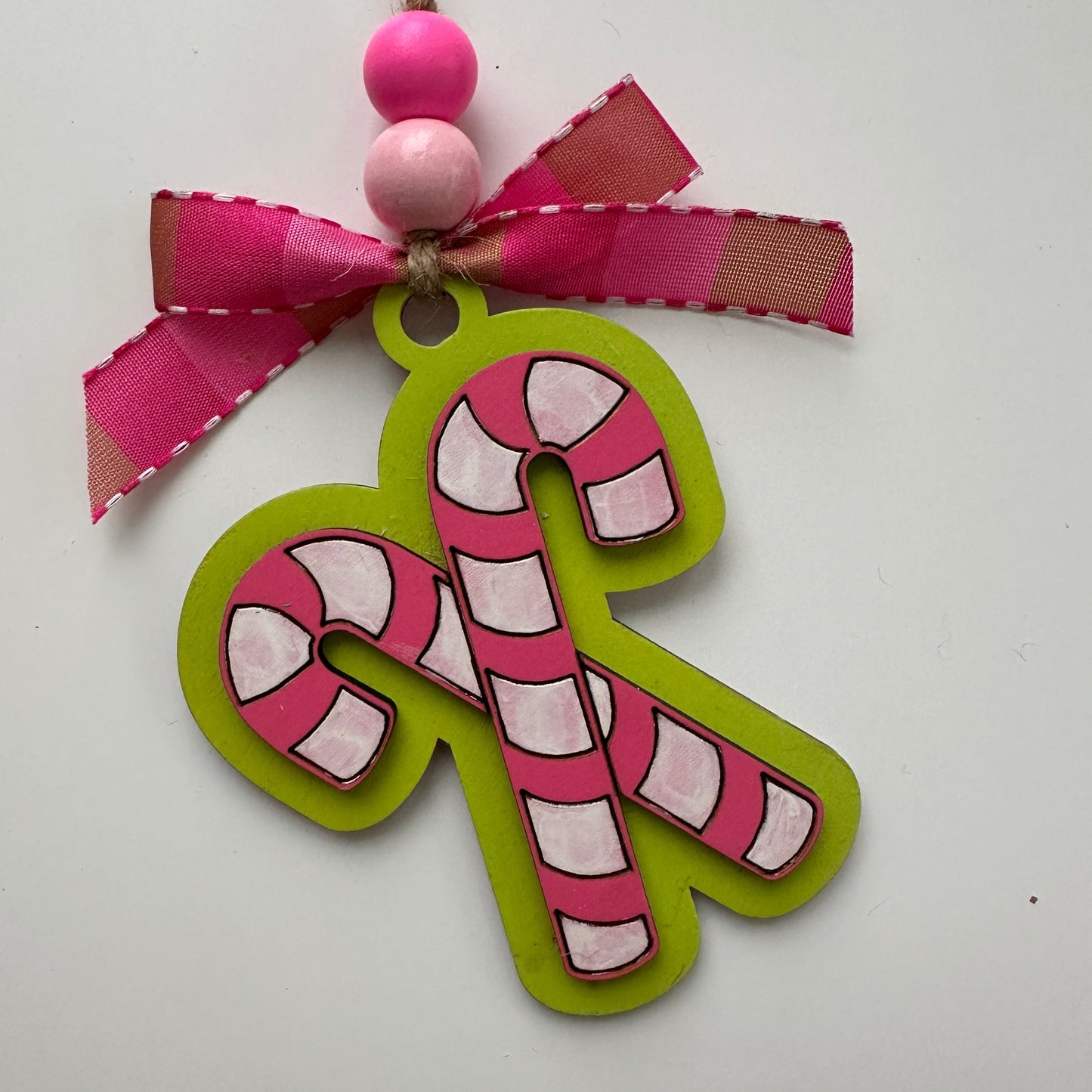 Decorative candy cane ornament with pink and green colors on a white background.