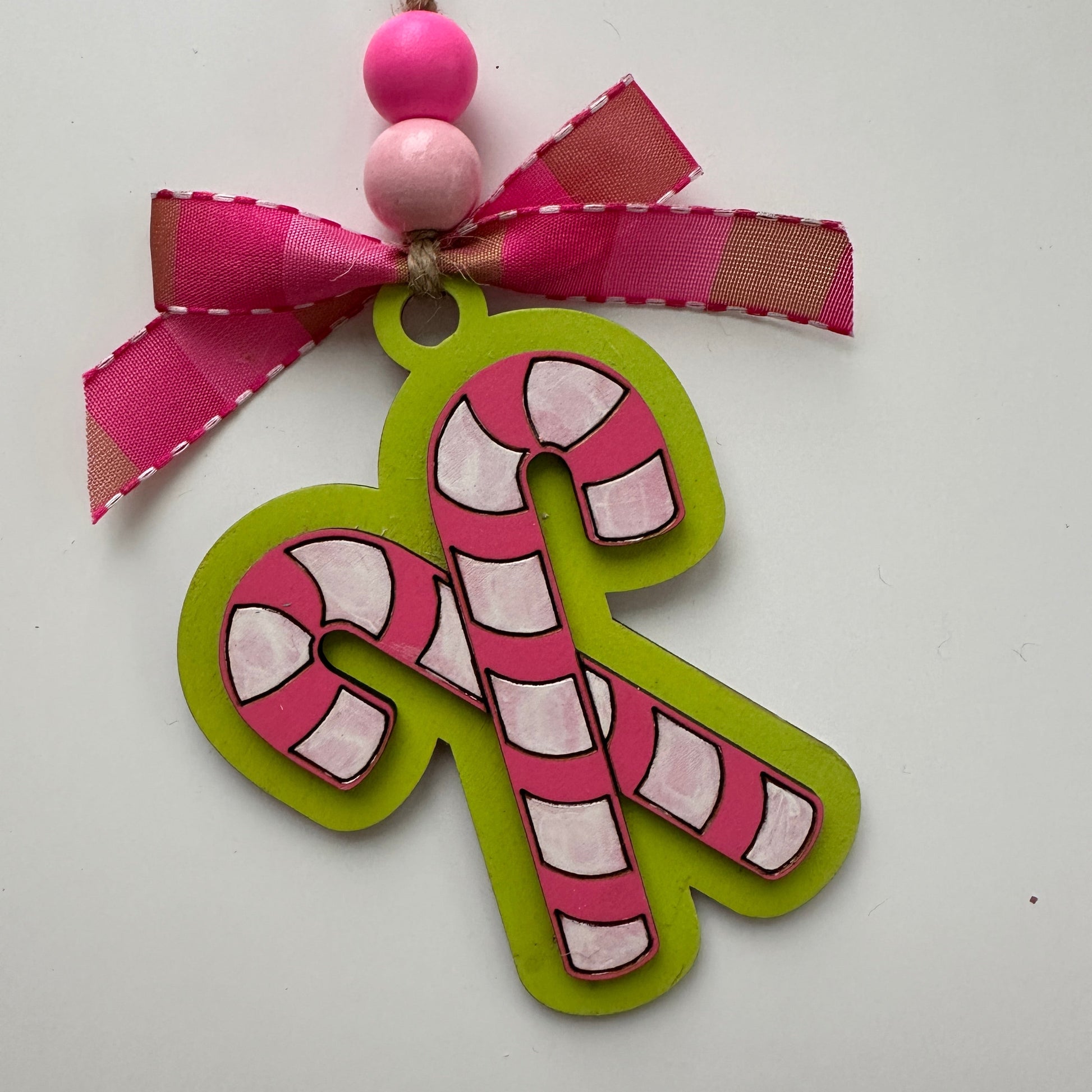 Decorative candy cane ornament with pink and green colors on a white background.