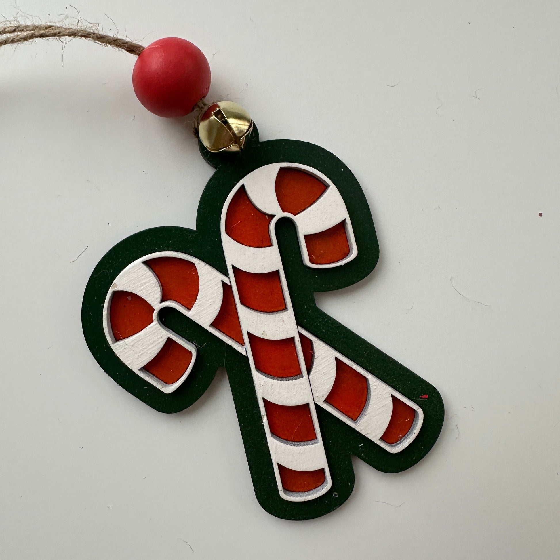 Decorative candy cane ornament with beads on a white background,