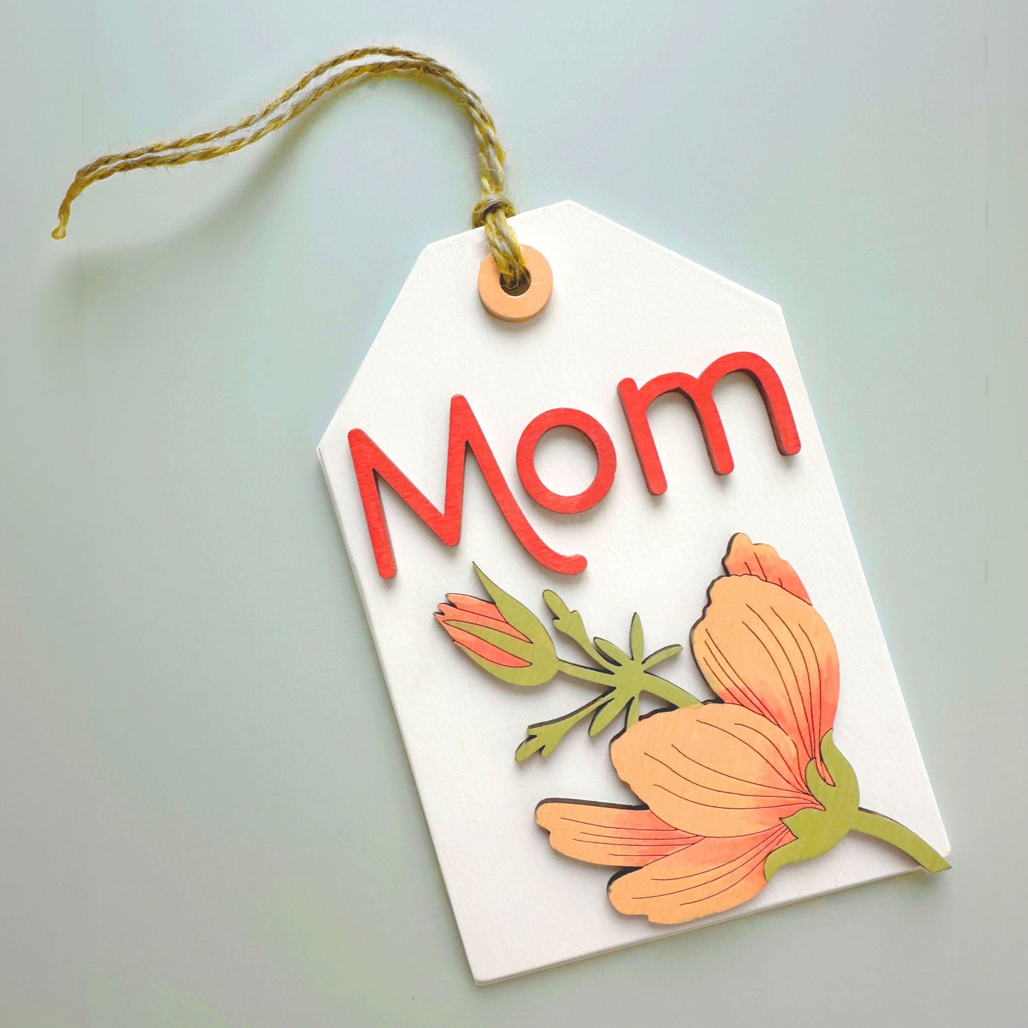 Decorative tag with 'Mom' and floral designs on a light gray background