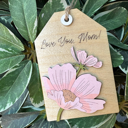 Gift tag with pink floral designs and 'Love You Most' text on a leafy background