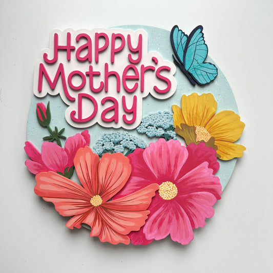 Decorative sign with 'Happy Mother's Day' text surrounded by colorful flowers and a butterfly on a light gray background.