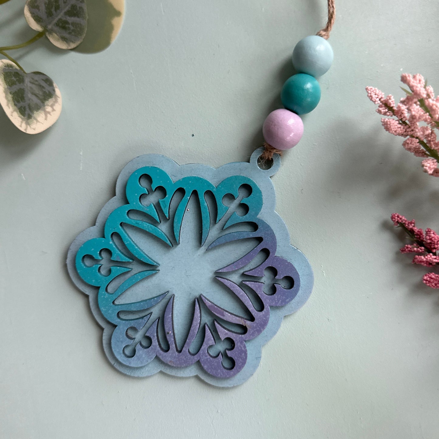 Decorative metal stencil with pastel colors on a light background with flowers and leaves.