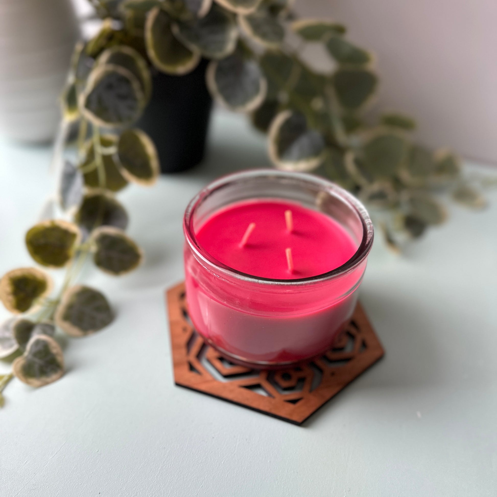 Red candle in a glass jar on a honeycomb trivet on a light background