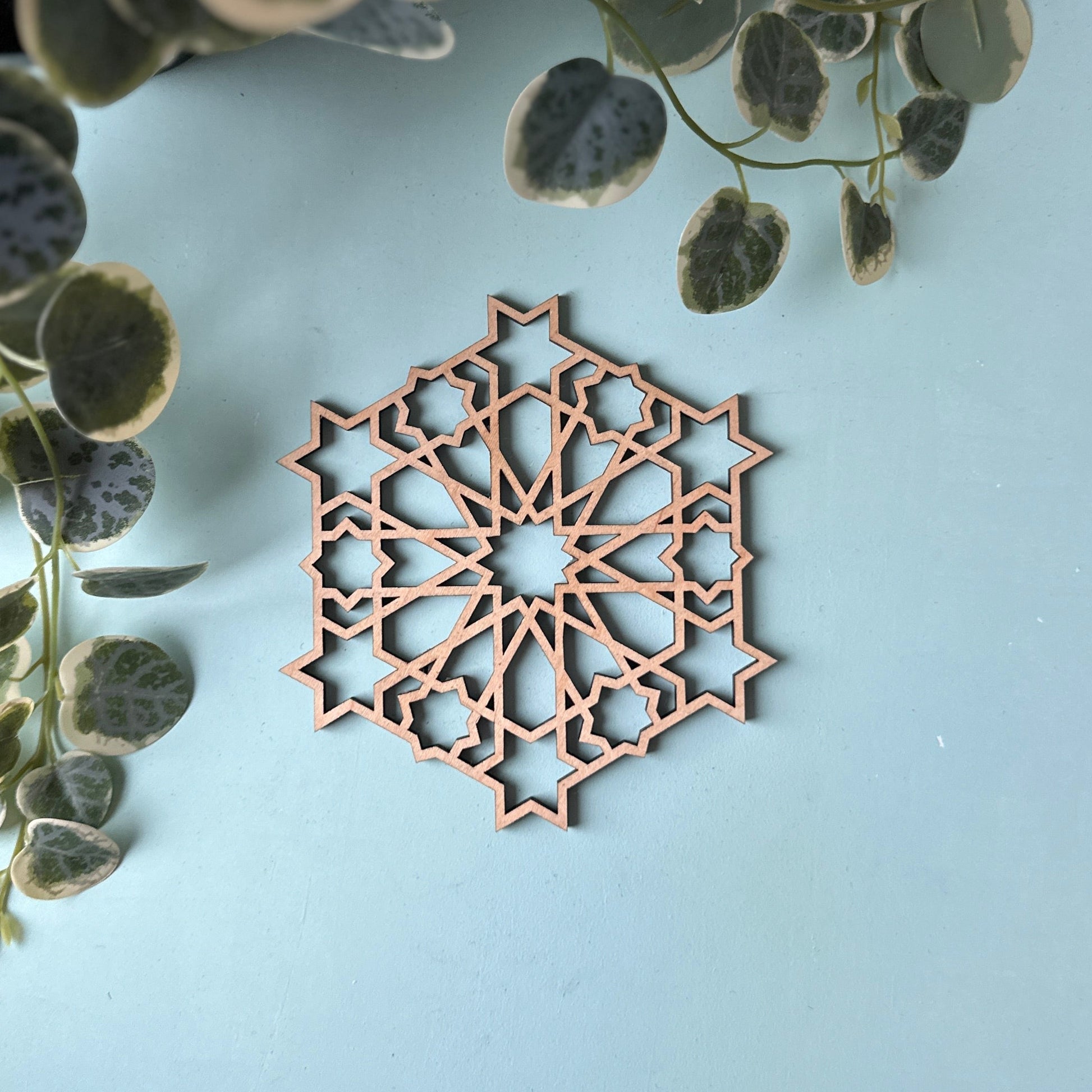 Decorative trivet with geometric pattern on a light surface next to a plant