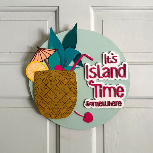 Decorative sign with pineapple, umbrella, and text 'It's Island Time somewhere' on a white door.