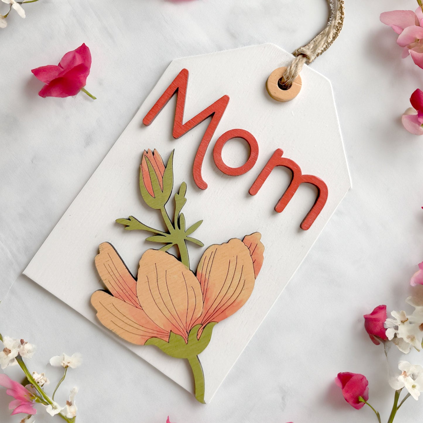 Card with 'Mom' and floral design surrounded by pink flowers on a light background