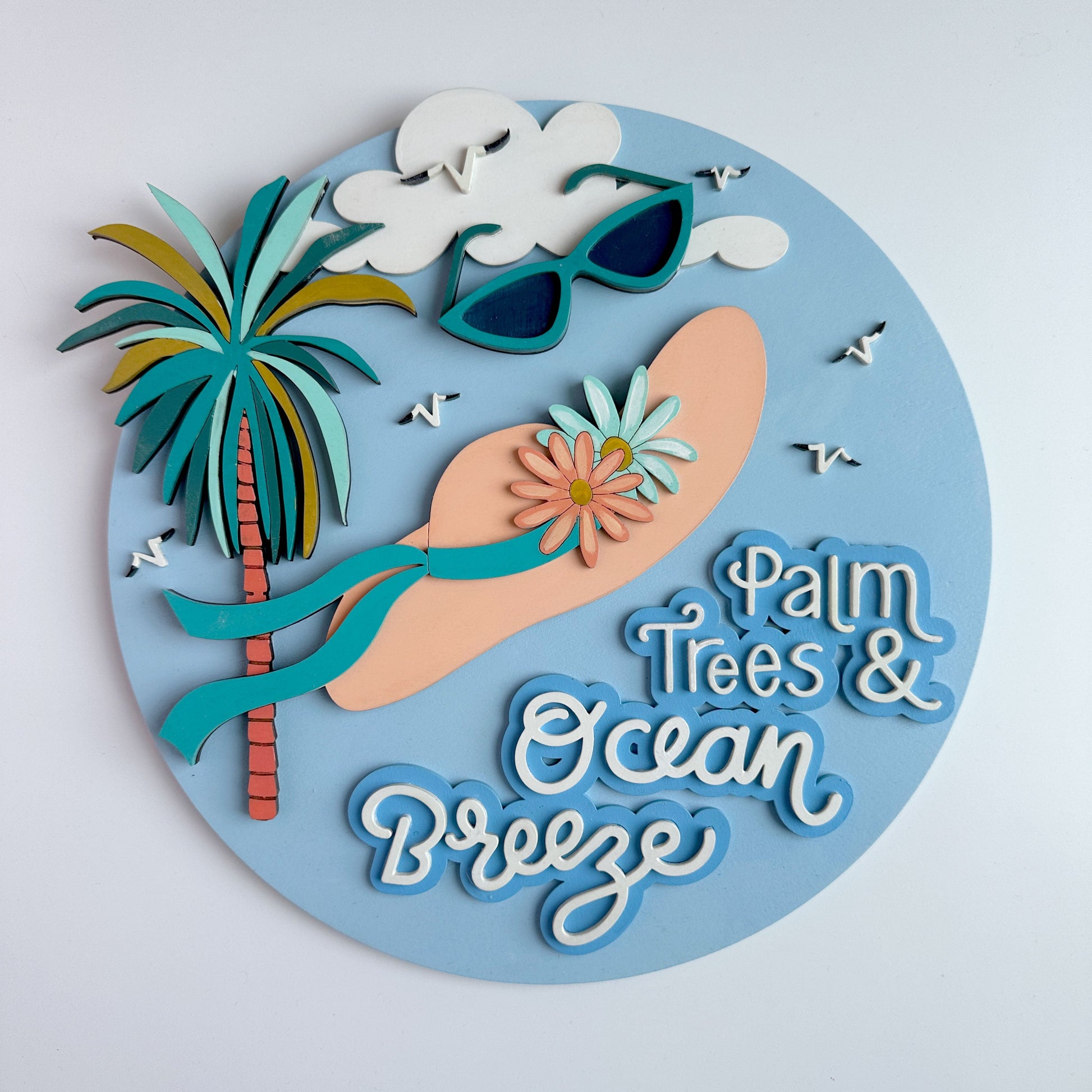 Decorative wall art with palm tree, sunglasses, surfboard, and 'Palm Trees & Ocean Breeze' text on a light blue background.