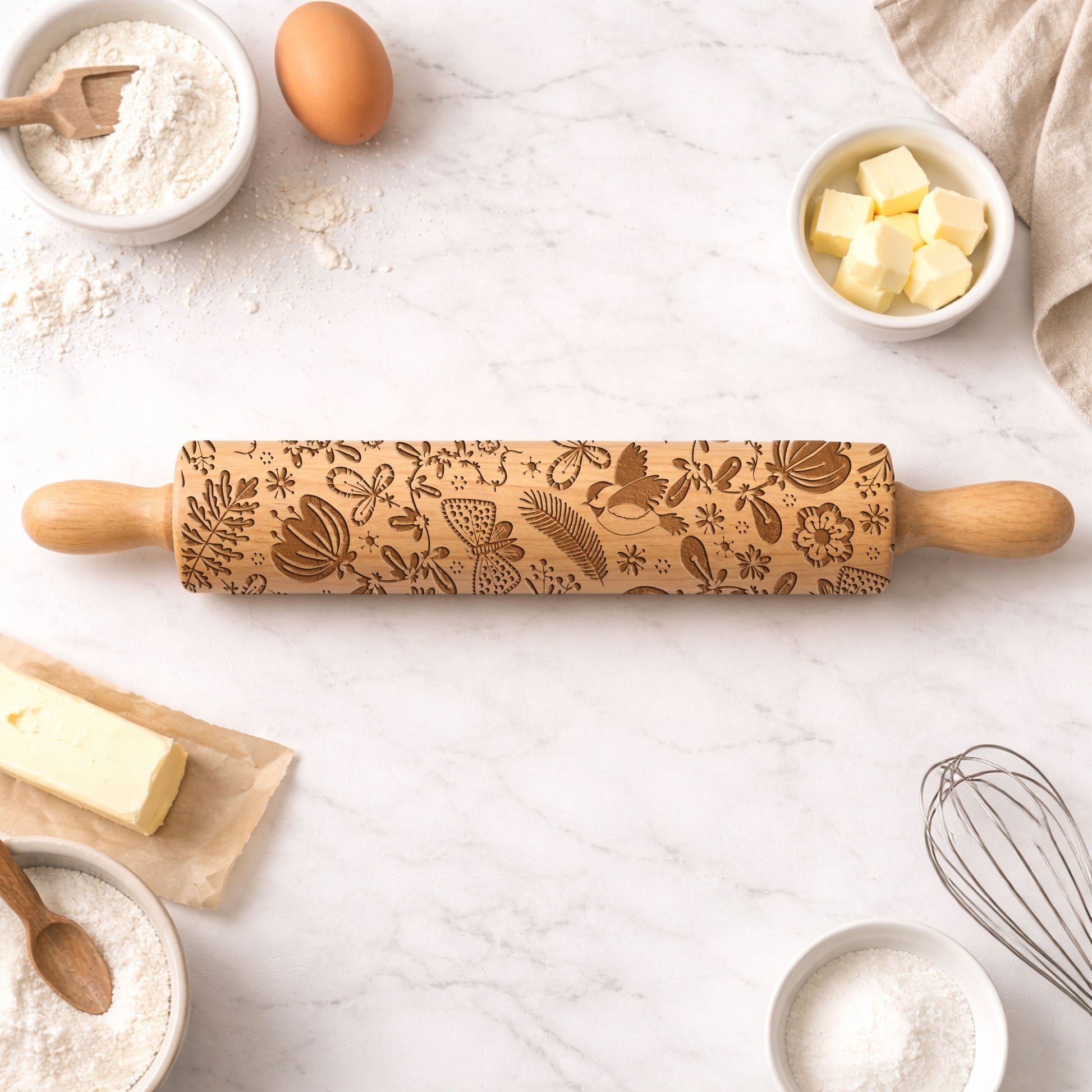Decorative rolling pin with embossed patterns on a kitchen counter with baking ingredients.