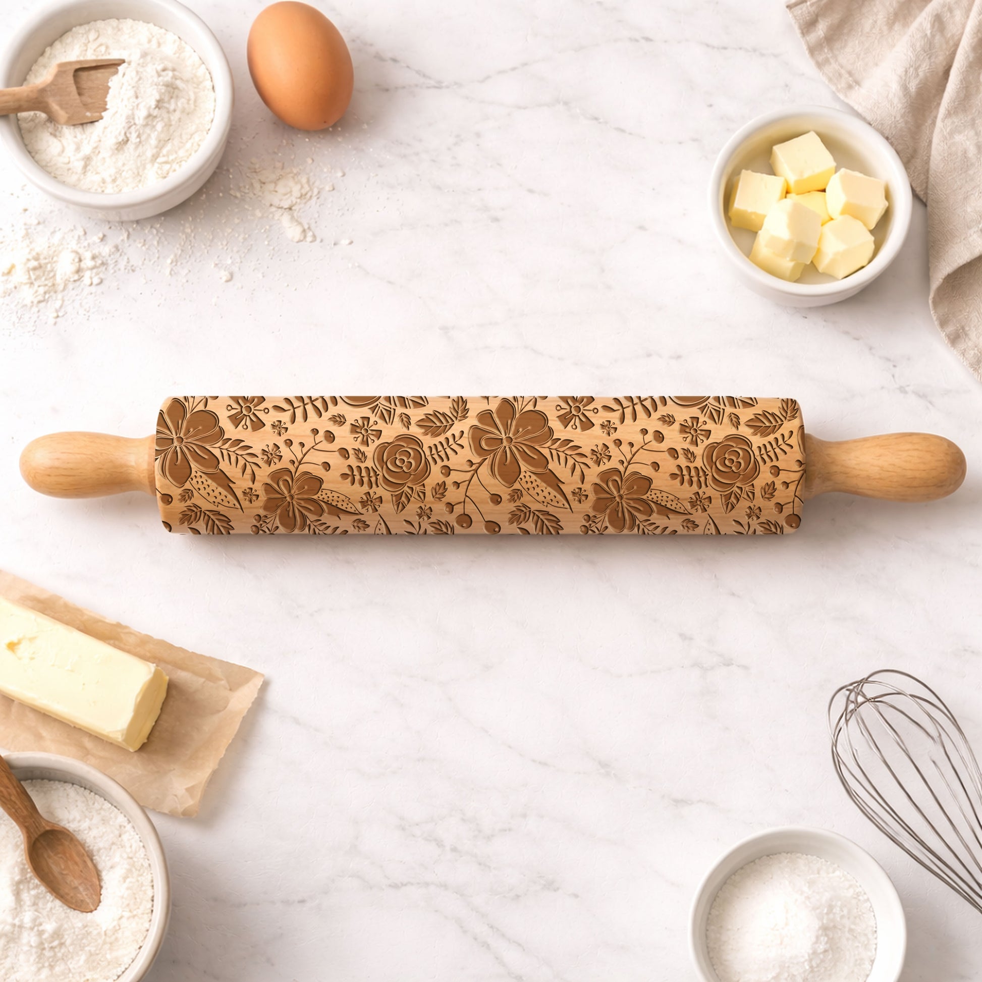 Decorative rolling pin with floral patterns on a kitchen counter with baking ingredients.