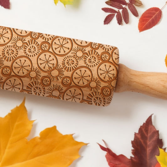 Wooden rolling pin with autumn leaf decorations on a white background