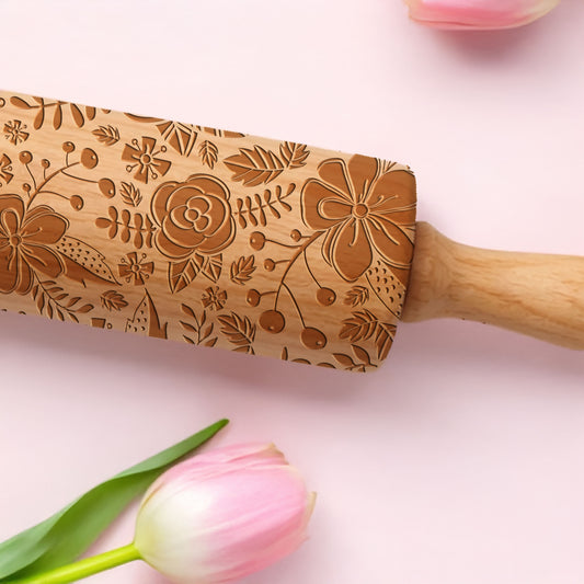 Wooden rolling pin with floral patterns on a pink background with tulips.